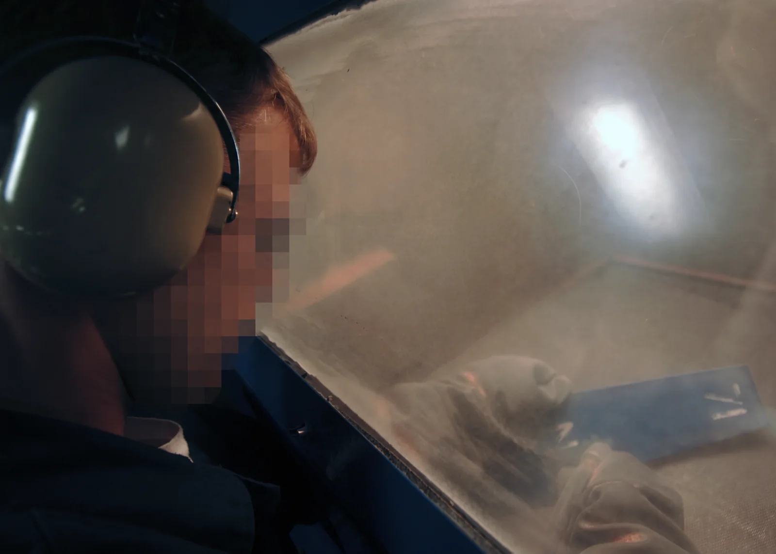 Arenado de una pieza metálica dentro de una cabina, fotografía ilustrativa de dominio público