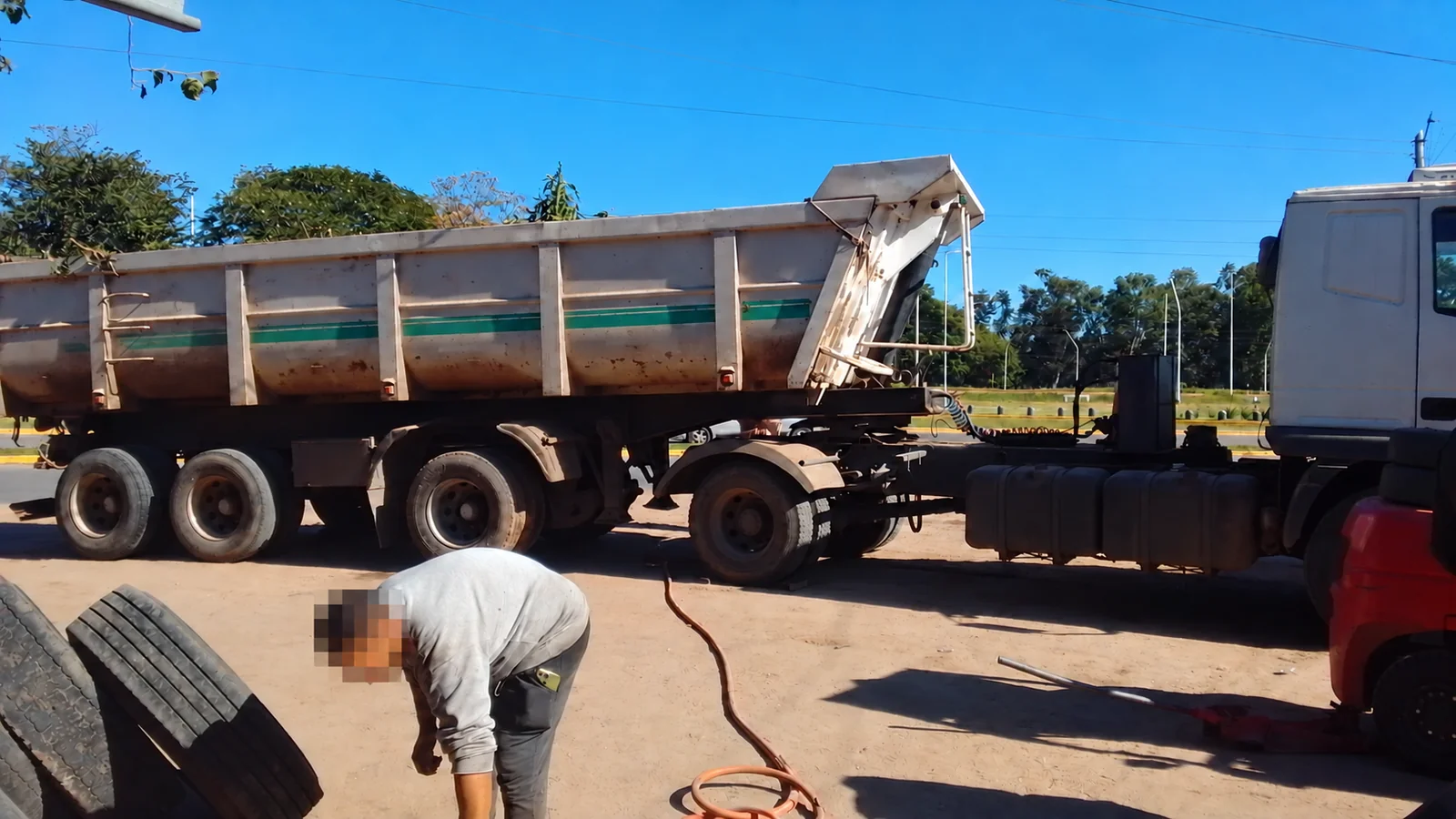 Trabajo de gomería junto a un camión con semirremolque y neumáticos